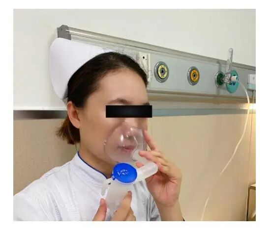 image_category: CLINICAL_PHOTO/Nebulization therapy demonstration | body_region: head | specialty: Respiratory Medicine | summary: A clinical demonstration of a nebulizer mask being used for aerosolized medication delivery in a hospital setting.